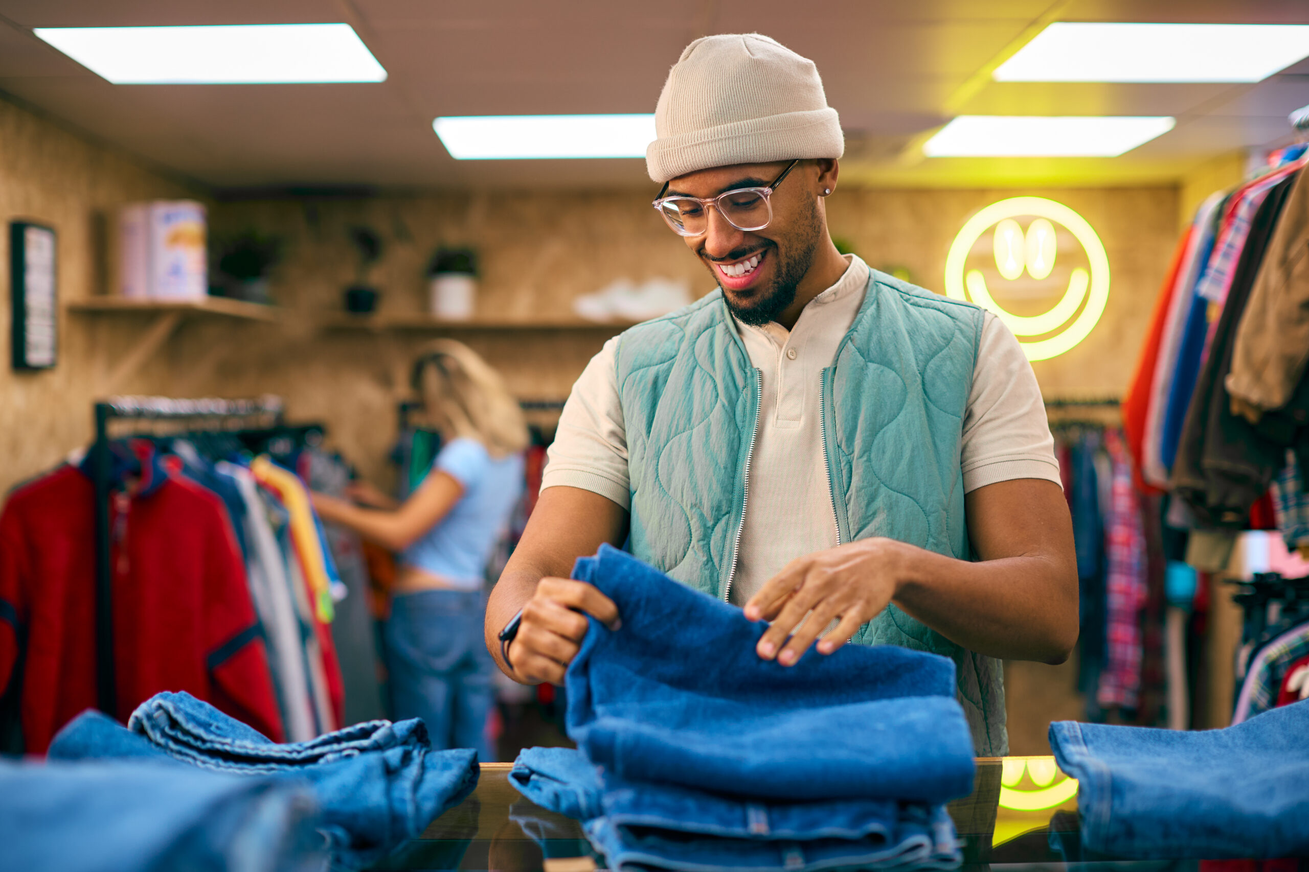 male sales assistant or customer sorting and looking at jeans in fashion store